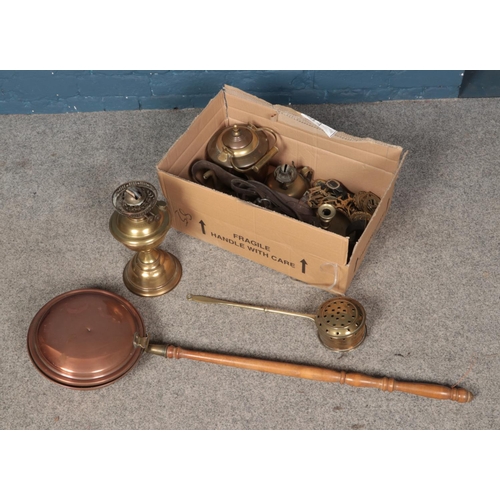 242 - A box of metalwares to include copper bed pan, brass paraffin lamp, horse brasses, etc.