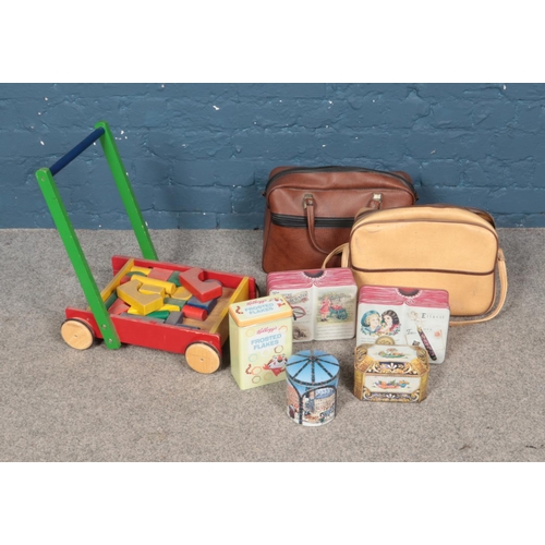 257 - A mix of leather holdalls, childs trolley with blocks and collectable tins