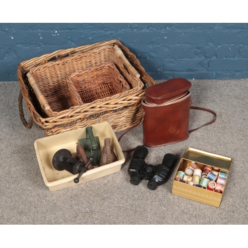 267 - Three wicker baskets with cast iron irons, cased binoculars and tin a bobbins.