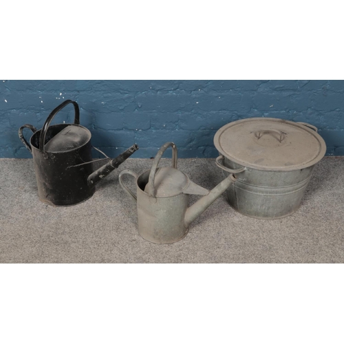 334 - Two metal watering cans with a metal pot and lid.