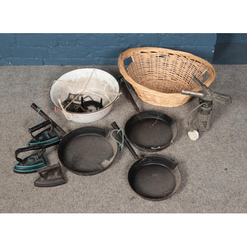 335 - A selection of metal items including Swain graduated cast iron pans and irons in a enamel bowl and w... 