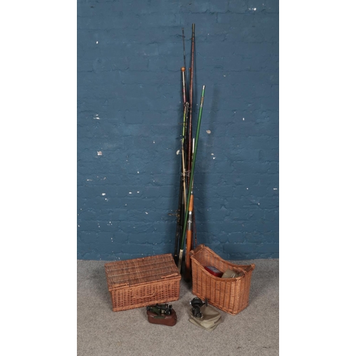 379 - A collection of vintage fishing rods along with reels and two wicker storage baskets.