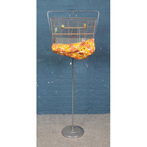 388 - A white metal birdcage on stand featuring toys and cover. Approx. 152cm tall.