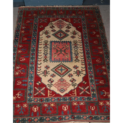 402 - A Turkish carpet featuring the ivory lozenge and geometric motifs framed by wide red borders. Approx... 