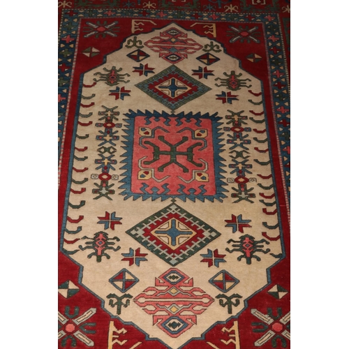 402 - A Turkish carpet featuring the ivory lozenge and geometric motifs framed by wide red borders. Approx... 