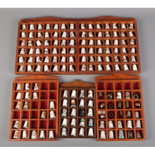 72 - A collection of mainly ceramic and white metal thimbles in five display frames.