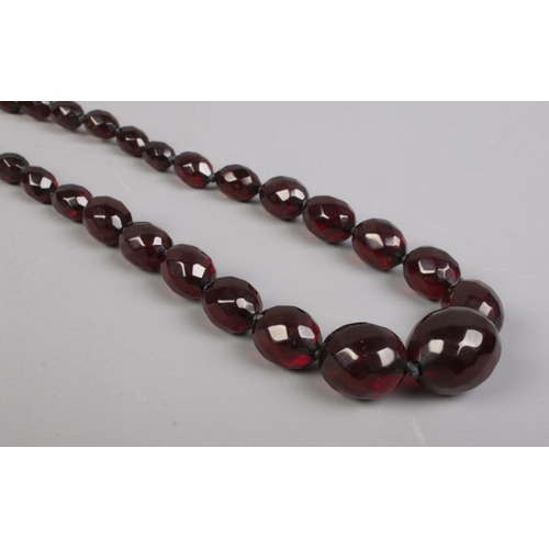 472 - A string of vintage faceted and graduated cherry amber coloured beads. 46g.