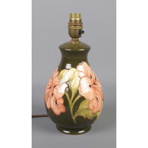 368 - A Moorcroft pottery table lamp in the Hibiscus pattern on a green background. Approx 26cm high.