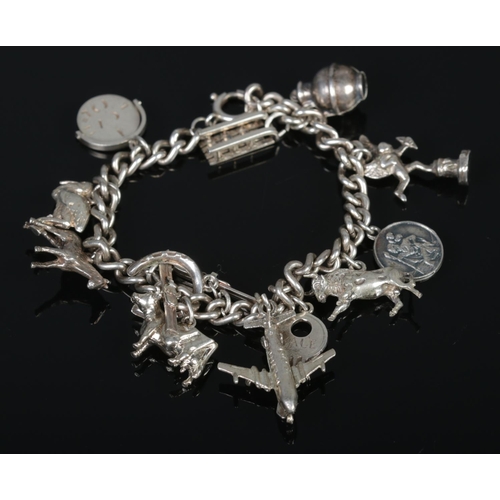 329 - A silver charm bracelet, containing charms including horseshoe, skis, bull and BOAC Comet IV. Total ... 