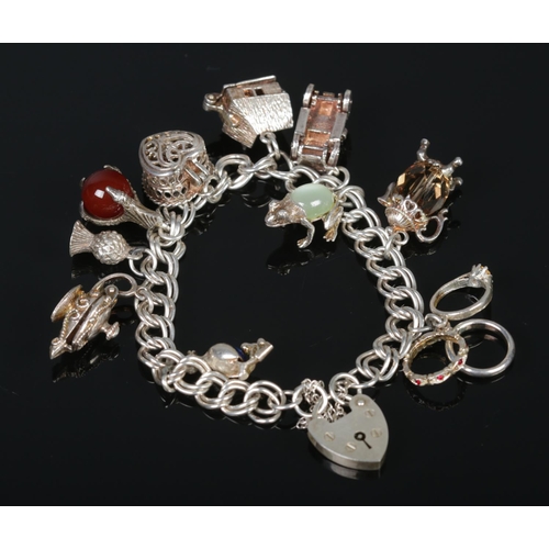 332 - A vintage silver charm bracelet, to include heart shaped casket, cart, claw clutching polished stone... 