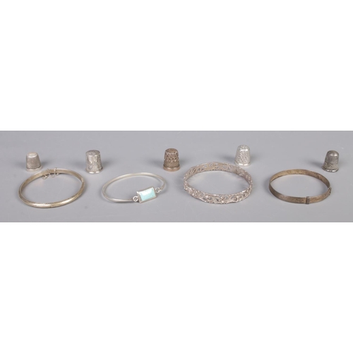 339 - Four silver bangles, together with five silver thimbles; all stamped. Total weight: 68.9g