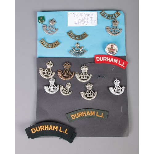 387 - A collection of Durham Light Infantry cap badges and patches including silver and mother of pearl ex... 