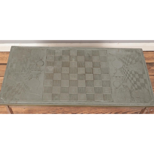 394 - A modern composite chess coffee table carved with board and chess motifs raised on white metal base.... 