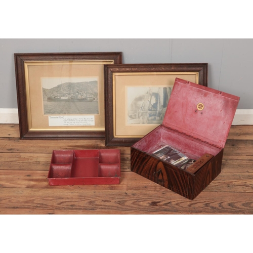 127 - A large metal cash tin with contents of pencils and postcards along with two framed pictures featuri... 