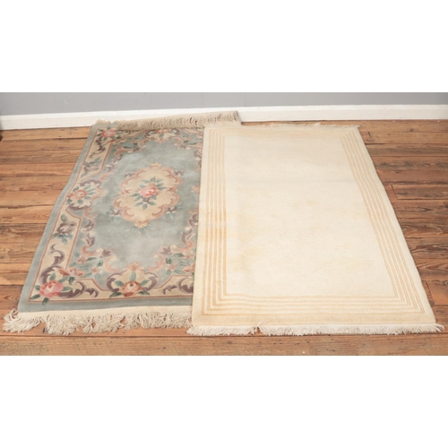 194 - Two wool fringed rugs including floral and cream geometric example.