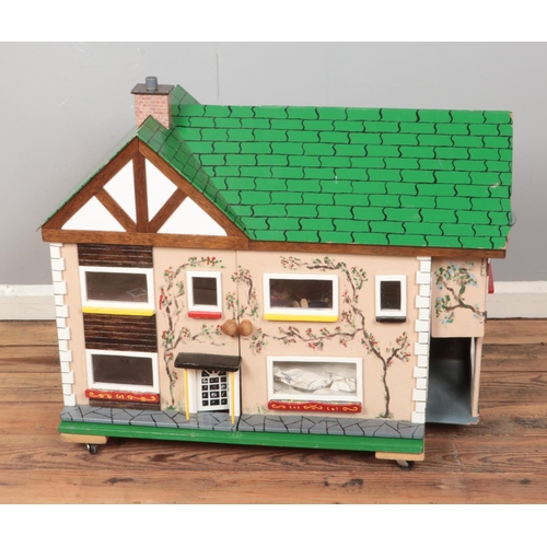 210 - A child's painted two story wooden dollhouse raised on castors and fitted with handles to side. Incl... 