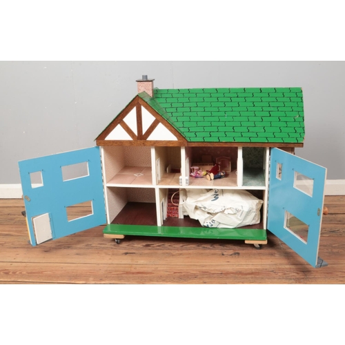 210 - A child's painted two story wooden dollhouse raised on castors and fitted with handles to side. Incl... 