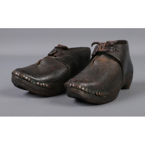 66 - A pair of antique child's shoes featuring leather uppers on 'horse-shoe style' wooden sole.