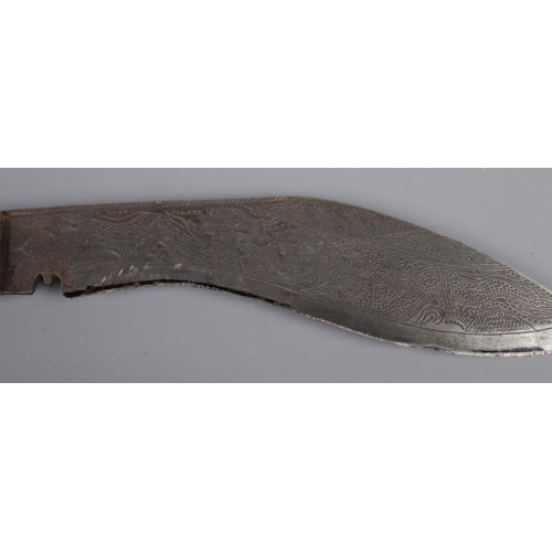 7 - A Nepal khukuri/gurka dagger engraved with dragon motifs. Includes sheath decorated with brass coins... 