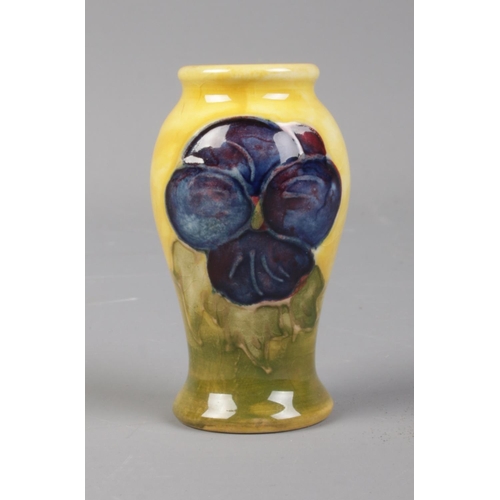 386 - A Moorcroft miniature pottery vase depicting pansies on yellow and green glaze. Height 5.5cm.