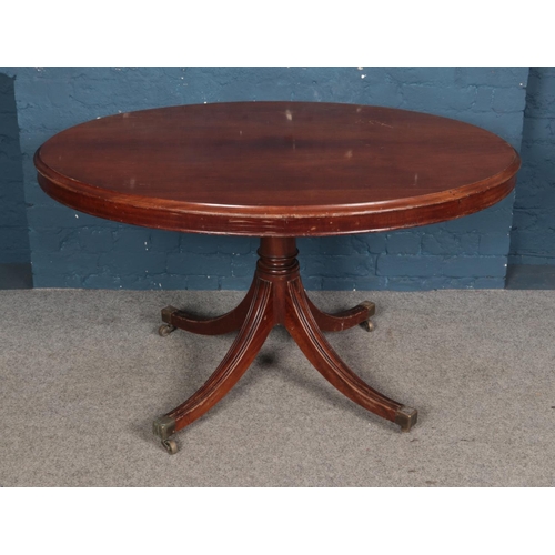 945 - A Regency mahogany oval table with four splayed legs. Raised on castors. Top 129x99cm.