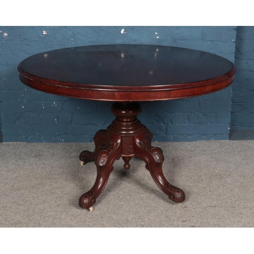 946 - A Victorian circular mahogany dining table. Raised on a turned central column support and four carve... 