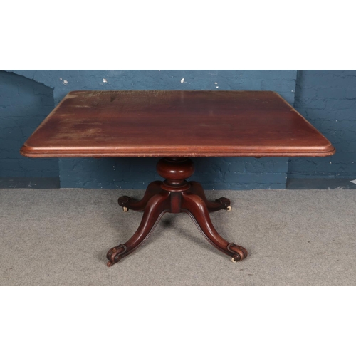 948 - A large rectangular mahogany dining table. Raised on turned central column support and four scrollin... 