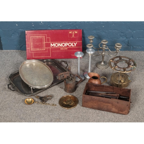 174 - A collection of metalwares including silver plate trays, candelabra, blow torch, Monopoly Deluxe and... 