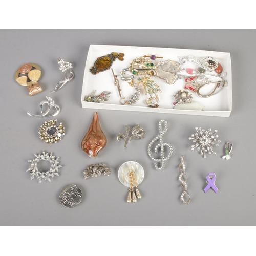 66 - A collection of costume jewellery brooches and pendants to include floral, music and glass examples.