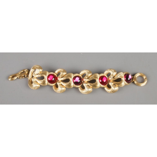 335 - A Givenchy gold plated bracelet with red coloured cabochon stones. Total length 18.5cm.