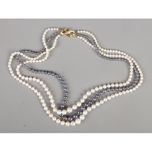 338 - A three row cultured pearl necklace with 18ct gold clasp. Clasp set with clear coloured stones.