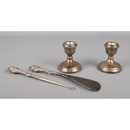 396 - A pair of dwarf filled silver candlesticks, together with two silver handled utensils. Hallmarks on ... 