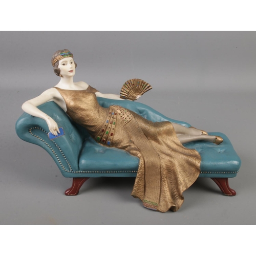 86 - A Coalport figure of a young maiden reclining on a chaise lounge. Titled 'Penny'.