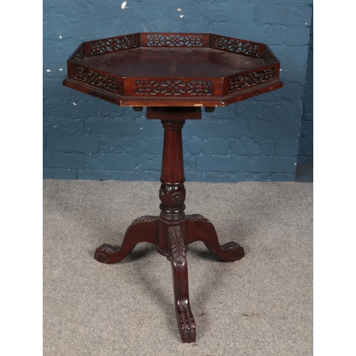 427 - A carved mahogany tripod table with fretwork gallery top and paw feet. Diameter of top 58cm.