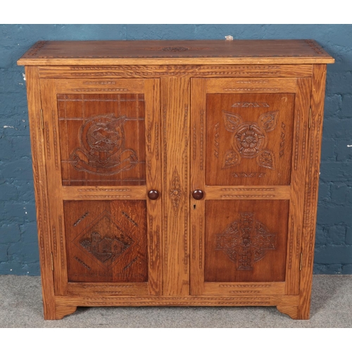 443 - A carved oak lead glazed bookcase with cupboard base. With panelled doors carved with four individua... 