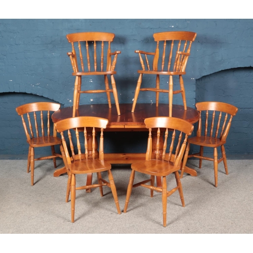 471 - An oval pine table with twin pedestal base together with folding hideaway leaf and six chairs.

Heig... 