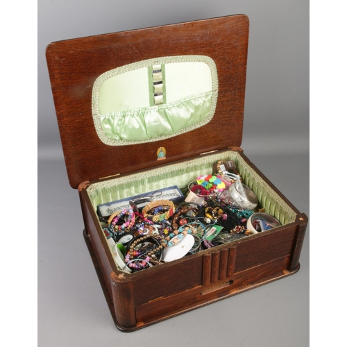 99 - A oak Marco workbox with contents of costume jewellery. Includes bangles, beads, necklaces, ear ring... 