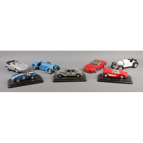 215 - Seven Burago model vehicles, some on plinths. To include 1965 Shelby Cobra, 1957 Chevrolet Corvette ... 