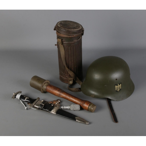 117 - A collection of replica German military items including stick grenade, helmet, dagger and metal cont... 