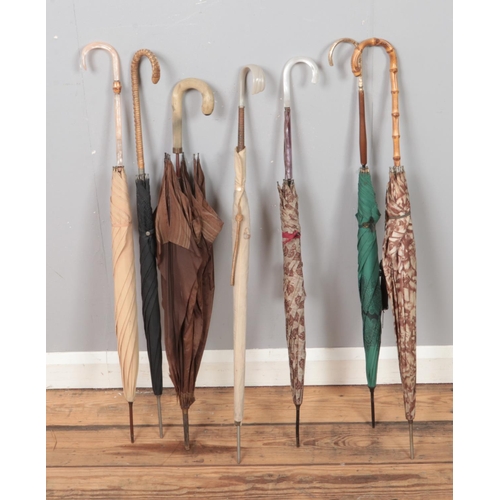 210 - A collection of vintage parasols with decorative handles to include wicker, bamboo and gemstone insp... 