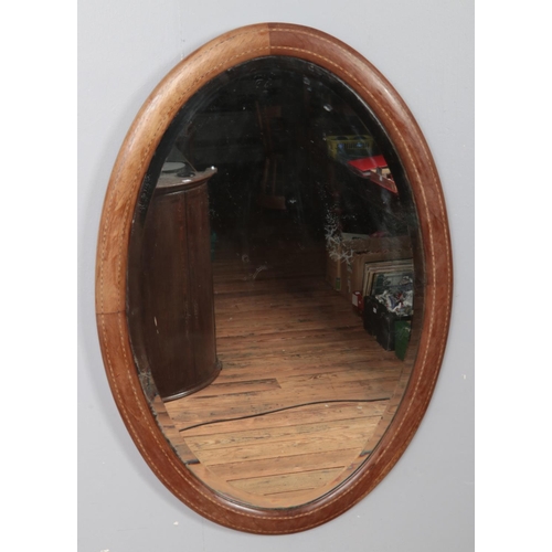 230 - An Edwardian inlaid oval bevel edge wall mirror. (82cm x 56cm)