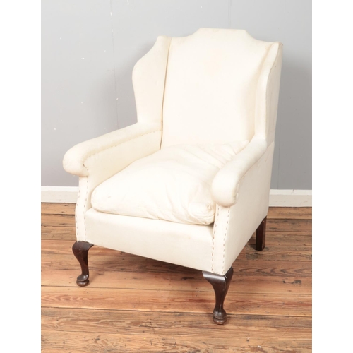 312 - A cream upholstered wing back armchair.