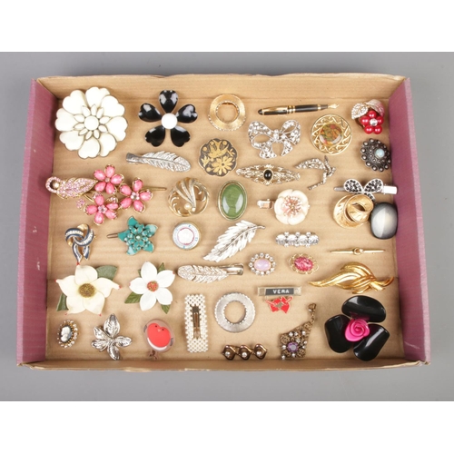 74 - A collection of costume jewellery brooches, dress clips, hair slides and badges. Approximately forty... 