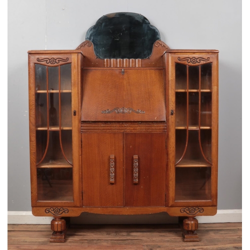 410 - A vintage oak side by side bureau with mirror top, glass fronted bookcases and partially fitted inte... 