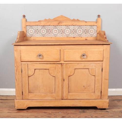 427 - A pine washstand, with cupboard and drawer front and tiled  back. Height: 108cm, Width: 106cm, Depth... 