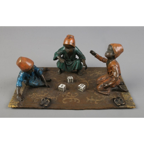 In the manner of Franz Bergman, an Austrian cold painted bronze figure group, three boys playing dice.