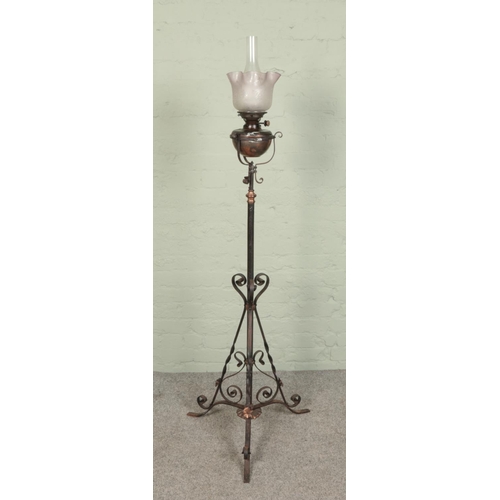 523 - A wrought iron standard oil lamp 
with glass shade and adjustable stem