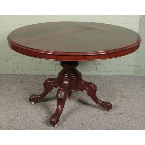 528 - A Victorian circular mahogany dining table. Raised on a turned central column support and four carve... 