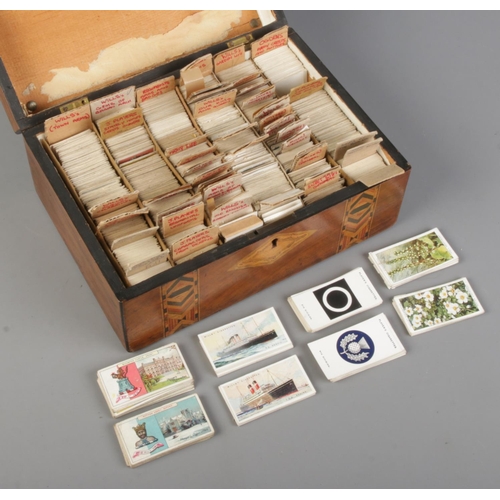 131 - A marquetry box with contents of cigarette cards. Includes Players, Wills, Ogdens, etc.