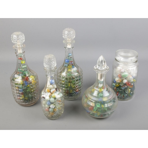 56 - A collection of marbles in glass bottles/decanters.